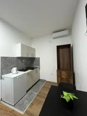 a kitchen with white appliances and a table in it at Apartmani Ćosić - Kuršumlijska banja in Kursumlijska Banja