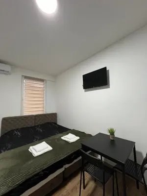 a bedroom with a bed and a table and a tv at Apartmani Ćosić - Kuršumlijska banja in Kursumlijska Banja