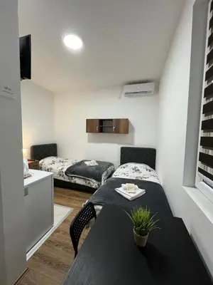 a small room with a bed and a table in it at Apartmani Ćosić - Kuršumlijska banja in Kursumlijska Banja