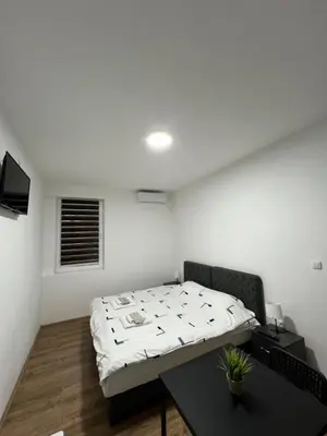 a bedroom with a bed and a table in it at Apartmani Ćosić - Kuršumlijska banja in Kursumlijska Banja