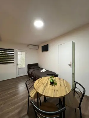 a room with a bed and a table and chairs at Apartmani Ćosić - Kuršumlijska banja in Kursumlijska Banja