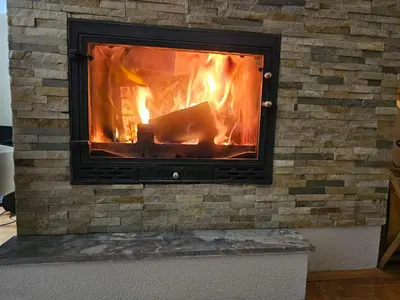 a brick fireplace with a fire in it at Apartman Čar11 in Kopaonik