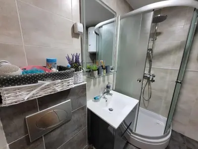 a bathroom with a sink and a shower with a mirror at Apartman Bubili in Vrnjačka Banja