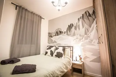 a bedroom with a bed with a mountain mural on the wall at Pukikop Apartman in Kopaonik