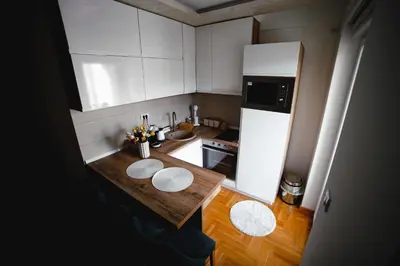 a small kitchen with a table and a refrigerator at Apartman VELUK in Vrnjci