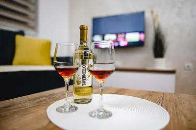 a bottle of wine and two glasses on a table at Apartman VELUK in Vrnjci
