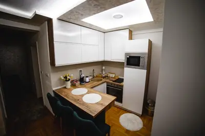 a small kitchen with a table and a refrigerator at Apartman VELUK in Vrnjci