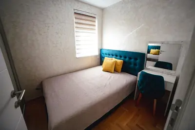 a small bedroom with a bed and a blue headboard at Apartman VELUK in Vrnjci