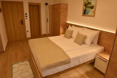 a bedroom with a large bed with white sheets and pillows at Hotel Zeleni Grad in Soko Banja