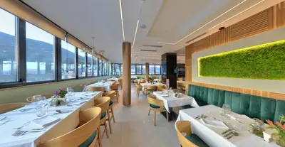 a restaurant with white tables and chairs and windows at Hotel Zeleni Grad in Soko Banja