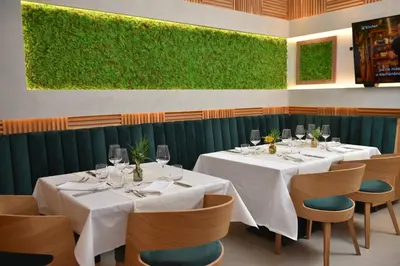a restaurant with white tables and chairs and a green wall at Hotel Zeleni Grad in Soko Banja