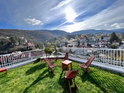 a balcony with chairs and a table on the grass at Hotel Zeleni Grad in Soko Banja