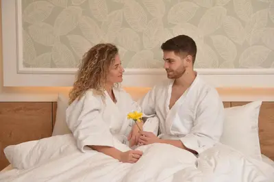 a man and a woman sitting on a bed at Hotel Zeleni Grad in Soko Banja