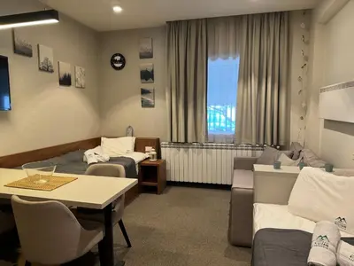 a room with two beds and a table and a couch at Apartmani Kilijan Kopaonik in Kopaonik