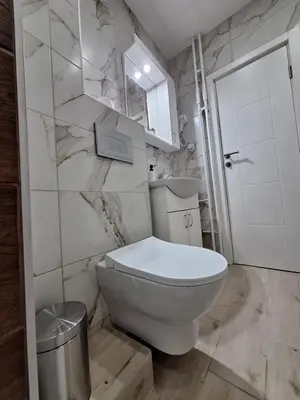 a white bathroom with a toilet and a sink at Relax Lux apartment Nis in Niš