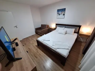 a small bedroom with a bed and a television at Relax Lux apartment Nis in Niš