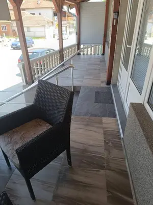 a hallway with a chair and a porch with windows at Apartman Lara in Kuršumlija