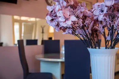 a white vase filled with purple flowers on a table at Apartman Lara in Kuršumlija