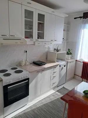a kitchen with white cabinets and a stove top oven at Apartman MIKA in Zaječar