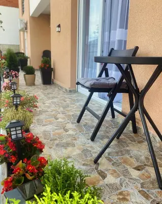 a black chair sitting on a patio with flowers at Apartman Amaris in Vrnjačka Banja
