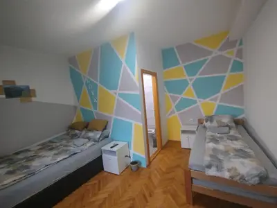 a bedroom with two beds and a geometric wall at V&U Sobe in Brzi Brod