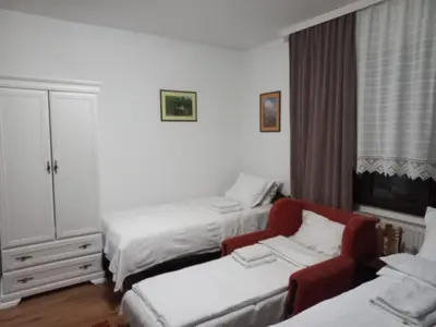 a bedroom with two beds and a red chair at B&B Vila Babin zub in Balta Berilovac