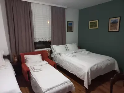 a hotel room with two beds and a chair at B&B Vila Babin zub in Balta Berilovac