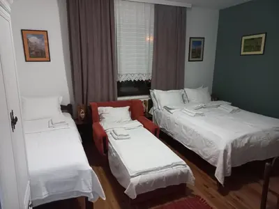 a room with two beds and a red chair at B&B Vila Babin zub in Balta Berilovac