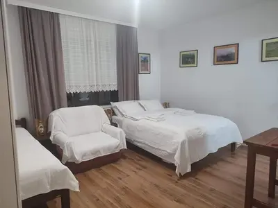 a hotel room with two beds and a chair at B&B Vila Babin zub in Balta Berilovac