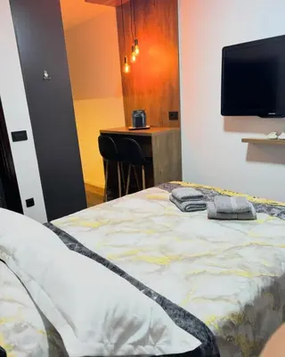 a bedroom with a bed with a tv on the wall at Stan na dan Kutak in Raška