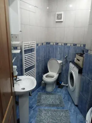 a blue tiled bathroom with a toilet and a sink at Apartman Mladenovic Center, free parking&wifi in Vranje