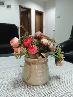 a vase filled with pink flowers on a table at Apartman Mladenovic Center, free parking&wifi in Vranje