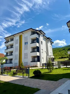 a large apartment building with benches in a park at Milka apartman Sokobanja in Soko Banja