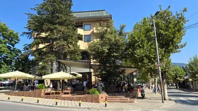 a building with tables and umbrellas on a city street at Hotel Vojvoda Putnik in Vranje