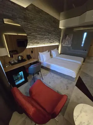 a bedroom with a bed and a chair and a tv at Hotel Vojvoda Putnik in Vranje
