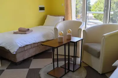 a bedroom with a bed and two chairs and a table at Apartmani Ad fines in Kuršumlija