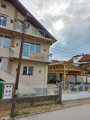 a building with a porch and a building with cars in front at SD PRENOĆIŠTE in Vranje