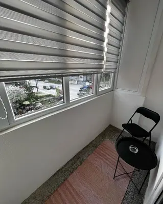 a room with a chair and a window with blinds at Apartman RISTIC in Vranje