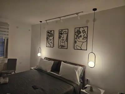 a bedroom with a bed with three pictures on the wall at Apartman Afrodita Lux 2 in Niš