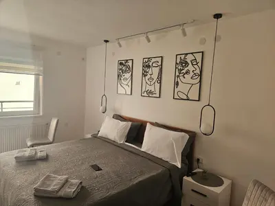 a bedroom with a bed with four pictures on the wall at Apartman Afrodita Lux 2 in Niš