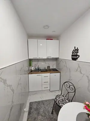 a kitchen with white cabinets and a table and chairs at Apartman Afrodita Lux 2 in Niš