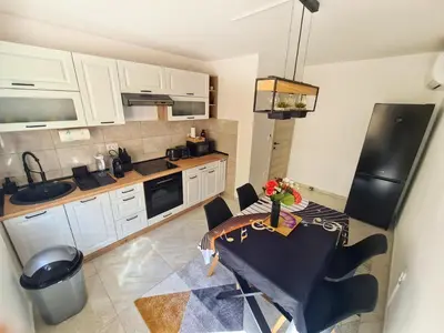 a kitchen with white cabinets and a table with flowers on it at Apartman Berlin Sokobanja 2 in Soko Banja