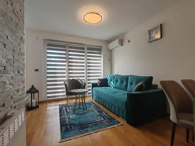 a living room with a green couch and a fireplace at Apartmani Harizma in Vrnjačka Banja