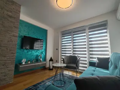 a living room with a blue couch and a table at Apartmani Harizma in Vrnjačka Banja