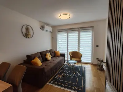 a living room with a brown couch and a table at Apartmani Harizma in Vrnjačka Banja