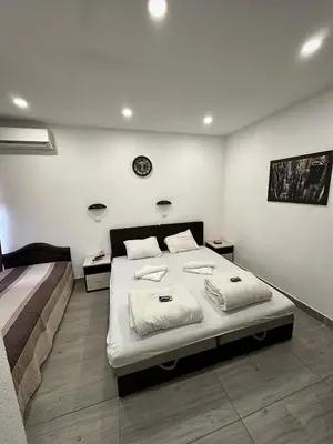 a bedroom with a bed and a clock on the wall at Apartmani Knez in Kruševac