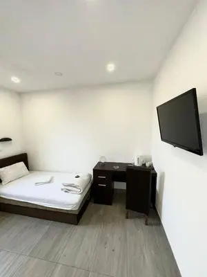 a room with a bed and a desk and a tv at Apartmani Knez in Kruševac