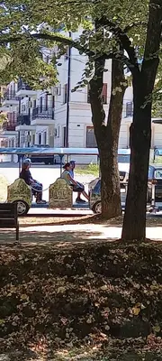 a group of people sitting on benches in a park at Apartman Mila 23 Vrnjačka Banja in Vrnjačka Banja