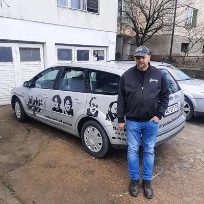 a man is standing in front of a car at AGAPE in Leskovac