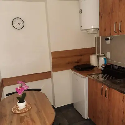 a kitchen with a wooden table and a clock on the wall at AGAPE in Leskovac